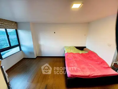 Spacious bedroom with large window and wooden flooring
