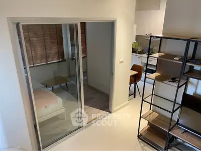 Modern studio apartment with sliding glass doors and open kitchen layout.