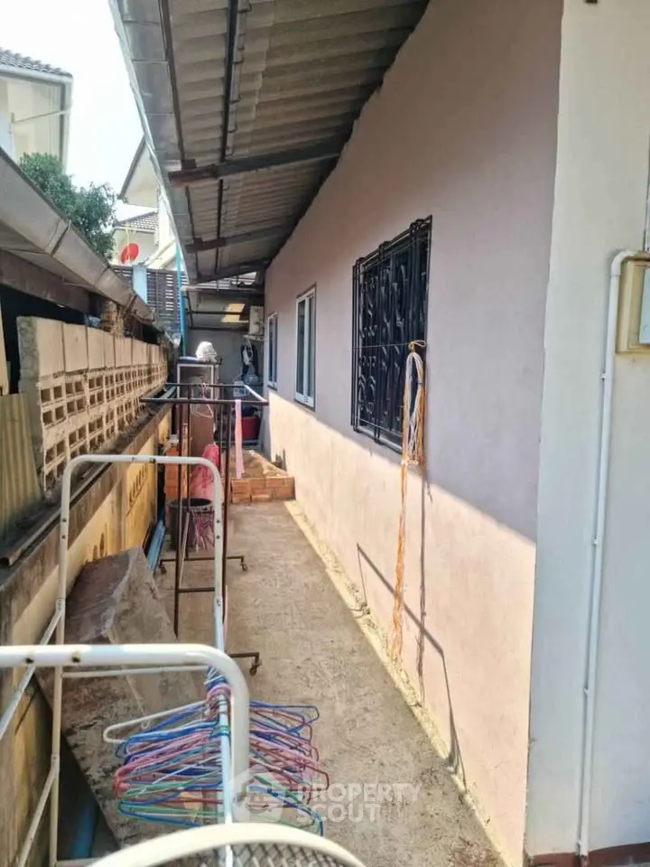 Narrow side passage with metal roof and laundry area in residential property