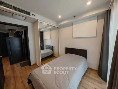 Cozy bedroom with wooden flooring and mirrored wardrobe in modern apartment
