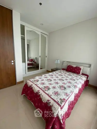 Cozy bedroom with floral bedding and mirrored wardrobe in modern apartment.