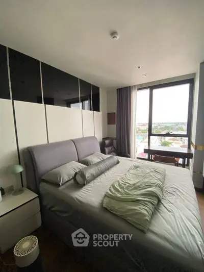 Spacious bedroom with modern decor and large window offering city view