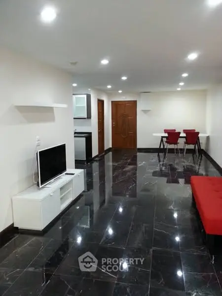 Spacious modern living room with sleek black flooring and stylish red accents.