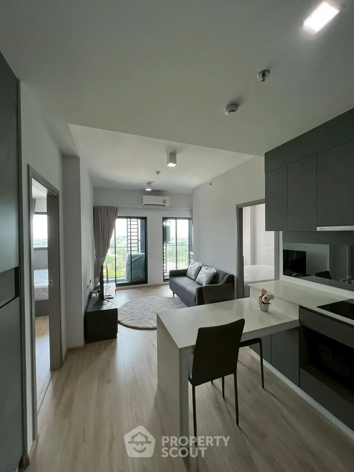Modern open-layout apartment with sleek kitchen and cozy living area, featuring a balcony with a scenic view.