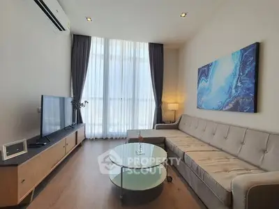 Modern living room with stylish decor, large window, and comfortable seating area.
