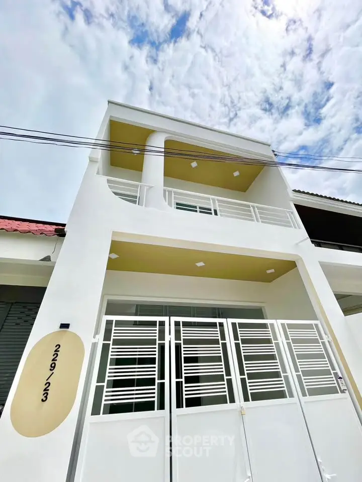 Modern white two-story house with unique architectural design and spacious balcony.