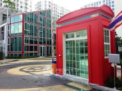Modern apartment complex with unique red architectural feature and glass facade.