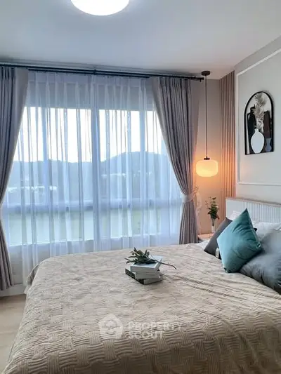 Cozy bedroom with large window and elegant decor, offering serene mountain views.