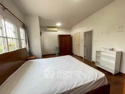 Spacious bedroom with wooden furniture and large windows for natural light.