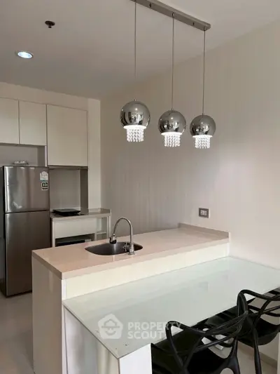Modern kitchen with sleek design, stainless steel appliances, and elegant pendant lighting.