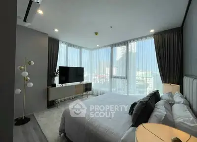 Luxurious bedroom with floor-to-ceiling windows and city view, modern decor and ample natural light.