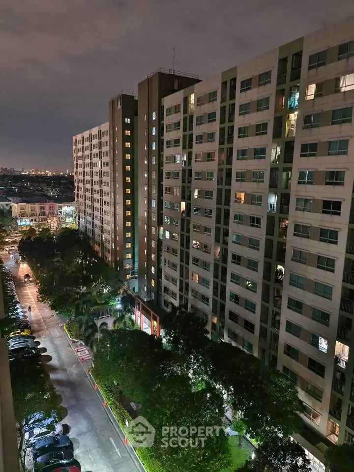Stunning night view of modern high-rise residential building with illuminated windows and lush greenery.
