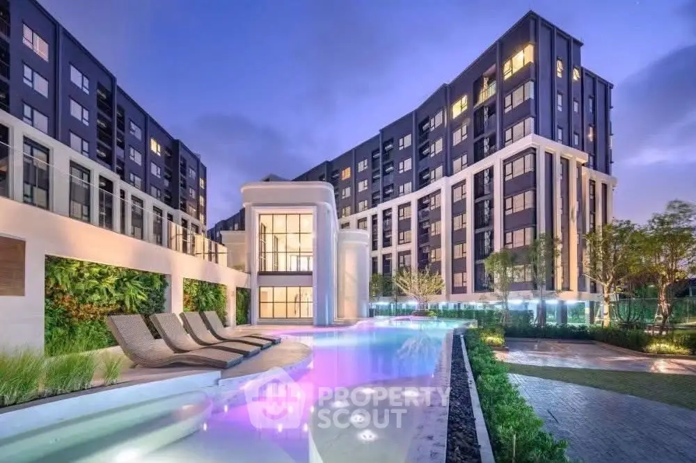Luxurious modern apartment complex with stunning pool and landscaped gardens at dusk.