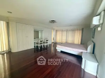 Spacious bedroom with elegant wooden flooring and ample natural light