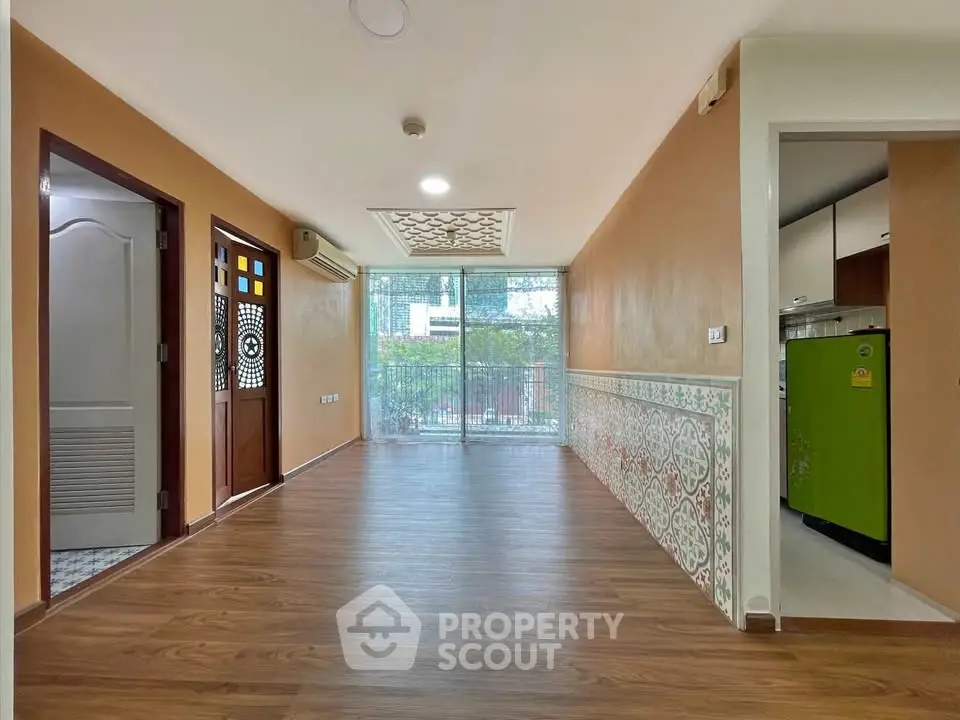 Spacious living room with wooden flooring and large windows offering city views.