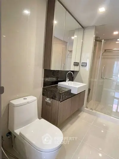 Modern bathroom with sleek fixtures and glass shower enclosure in luxury apartment.
