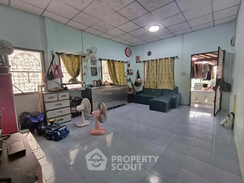 Spacious living room with tiled floor, cozy seating, and ample natural light from large windows.