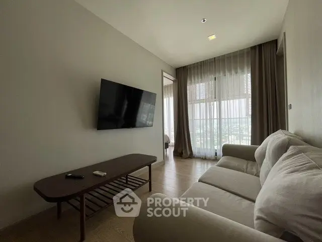 Modern living room with wall-mounted TV and large window offering natural light and scenic views.