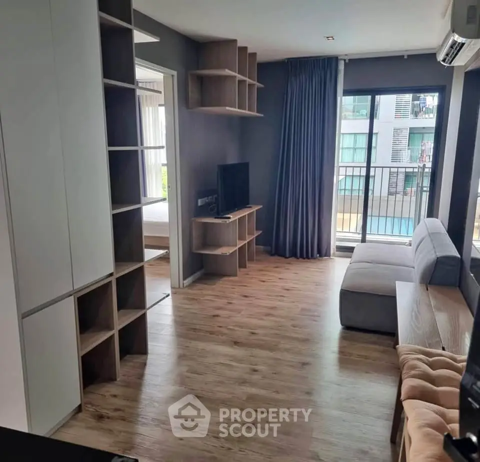 Modern living room with wooden flooring, cozy sofa, and balcony view in a stylish apartment.