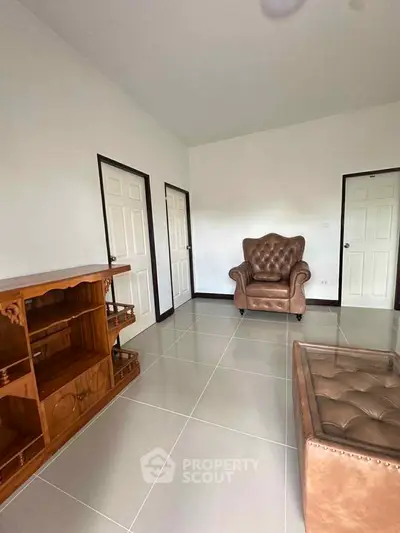 Spacious living room with elegant leather armchair and wooden cabinet, perfect for cozy gatherings.