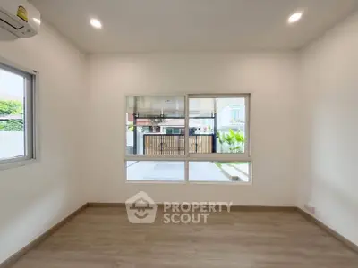 Spacious unfurnished room with large windows and wooden flooring, perfect for customization.