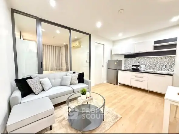 Modern open-layout living room with sleek kitchen, cozy sofa, and stylish decor in a bright apartment.