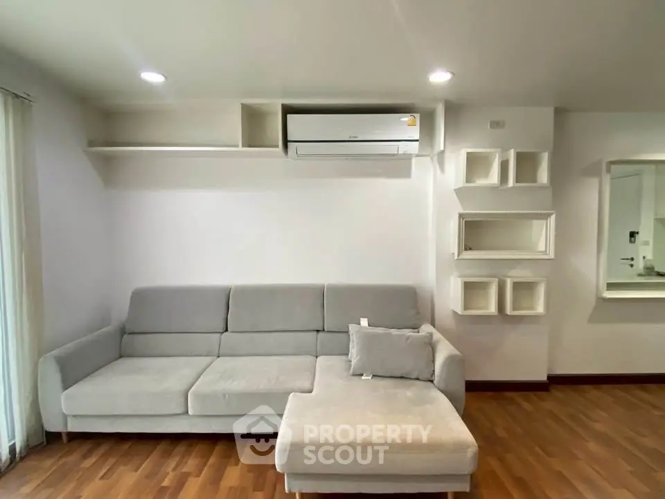 Modern living room with sleek gray sofa and wall-mounted air conditioner, perfect for comfortable living.