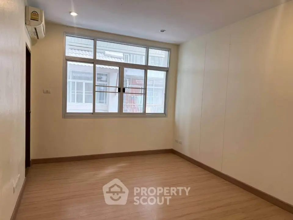 Spacious empty room with large window and wooden flooring, ideal for customization.