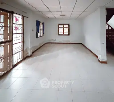 Spacious empty room with tiled floor and large windows, perfect for customization.