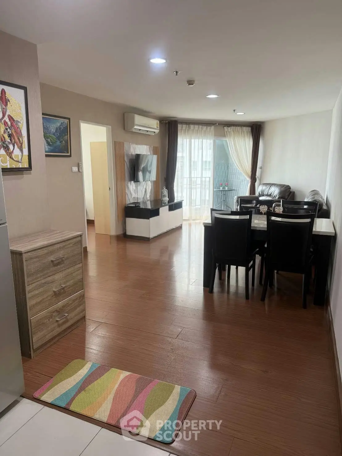 Spacious living room with dining area and modern decor in a well-lit apartment.
