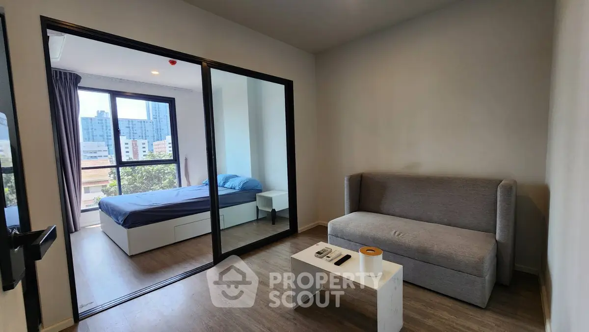 Modern apartment with cozy living room and bedroom featuring large windows and city view.