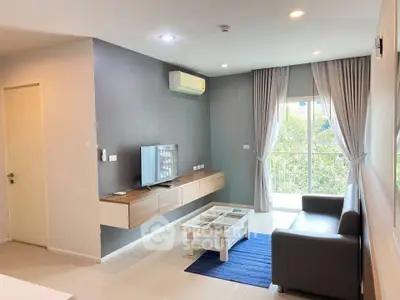 Modern living room with sleek furniture and large window offering natural light.