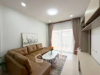 Modern living room with brown leather sofa and large window with sheer curtains.