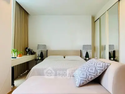 Modern bedroom with stylish decor, large mirror closet, and cozy seating area.