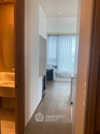 Modern apartment hallway leading to a bright living area with floor-to-ceiling windows.