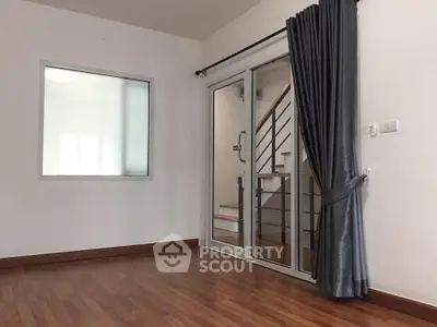 Spacious room with wooden flooring and sliding glass doors leading to staircase.