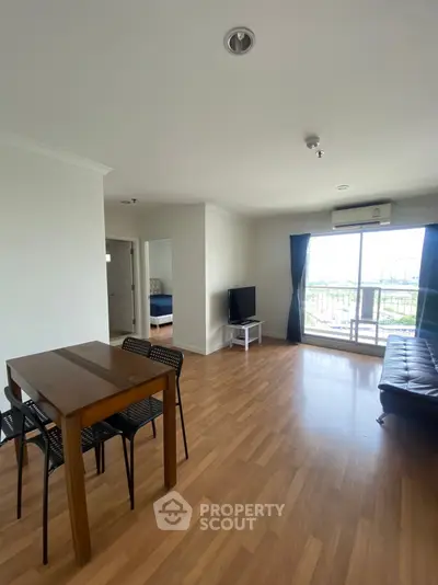 Spacious living room with wooden flooring and balcony view in modern apartment.