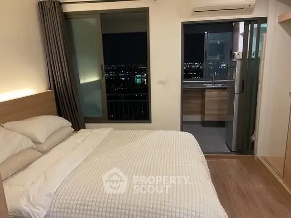 Modern bedroom with city view and balcony access at night