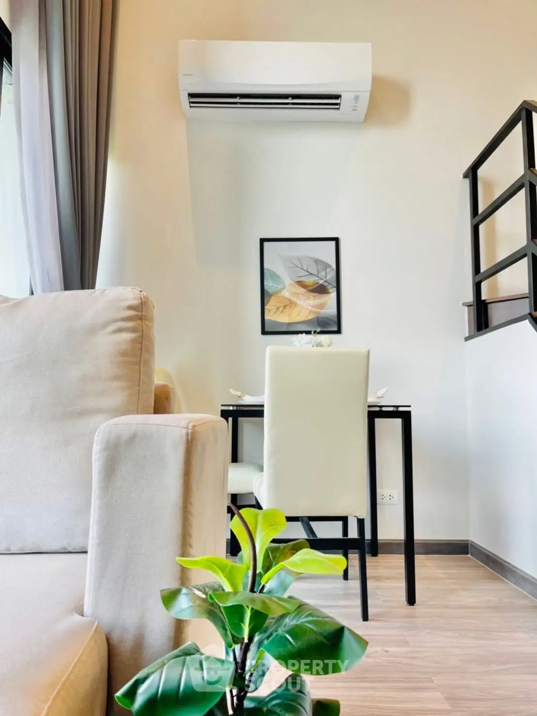 Modern living room with air conditioning and stylish decor, featuring a cozy dining area and lush indoor plant.
