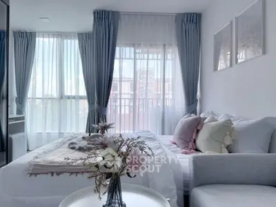 Elegant bedroom with large windows and stylish decor, featuring soft pastel accents and abundant natural light.