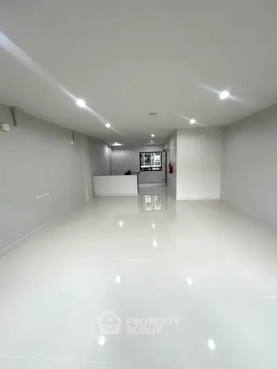 Spacious modern interior with glossy white flooring and recessed lighting, ideal for versatile use.