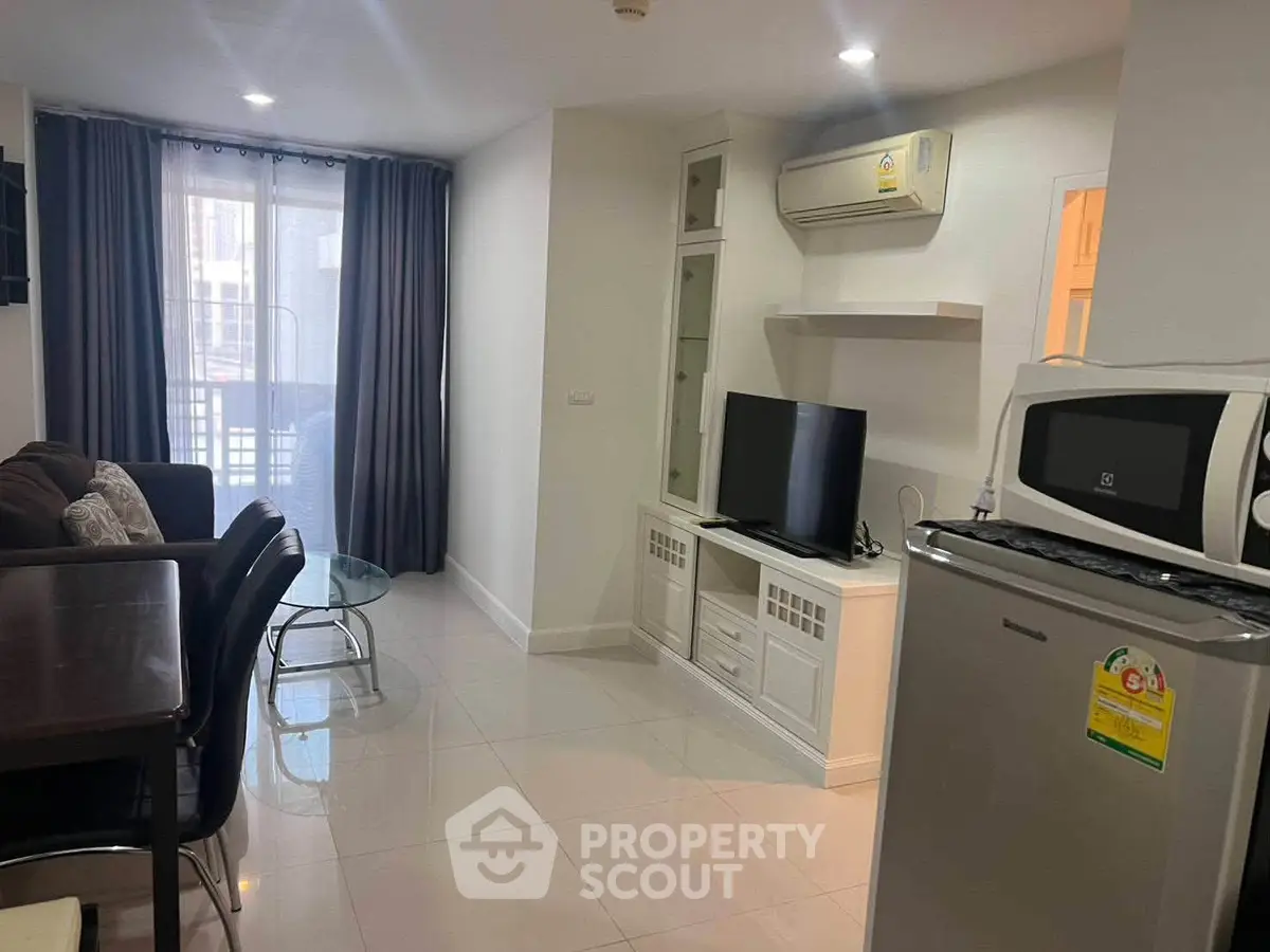 Modern living room with dining area and kitchen appliances in a cozy apartment.