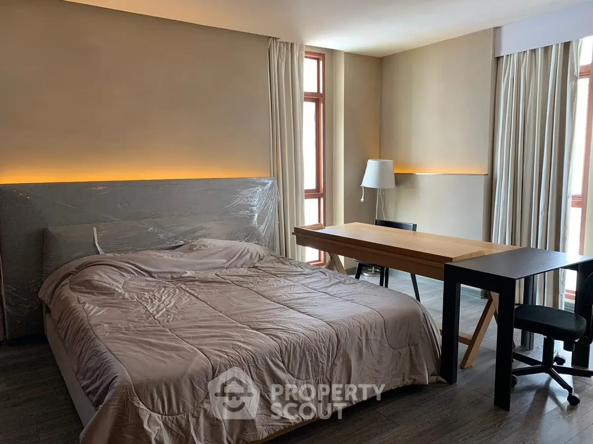 Modern bedroom with cozy lighting and study desk, perfect for relaxation and work.