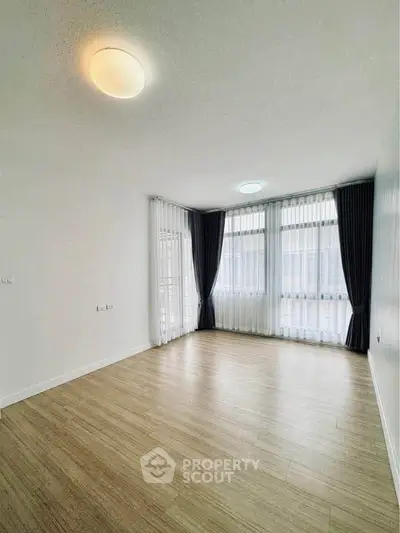 Spacious empty room with large windows and elegant curtains, perfect for customization.