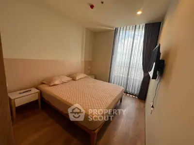 Modern bedroom with large window and wall-mounted TV in a stylish apartment.