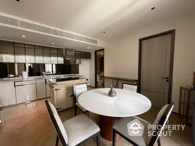 Elegant open-layout kitchen with modern appliances and a sleek marble dining table, complemented by natural light and tasteful decor.