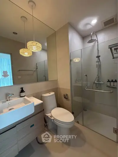 Modern bathroom with glass shower, elegant lighting, and sleek fixtures.