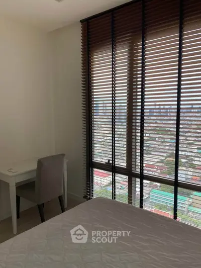 Modern bedroom with city view through large windows and stylish blinds, featuring a cozy study desk.