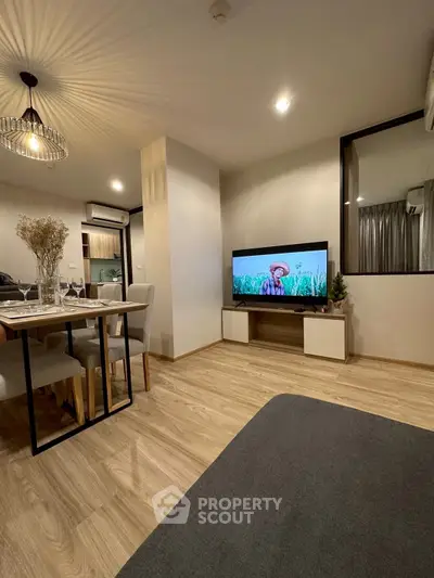 Modern living room with stylish decor and open dining area, featuring elegant lighting and wooden flooring.