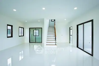 Spacious modern living room with sleek staircase and large windows